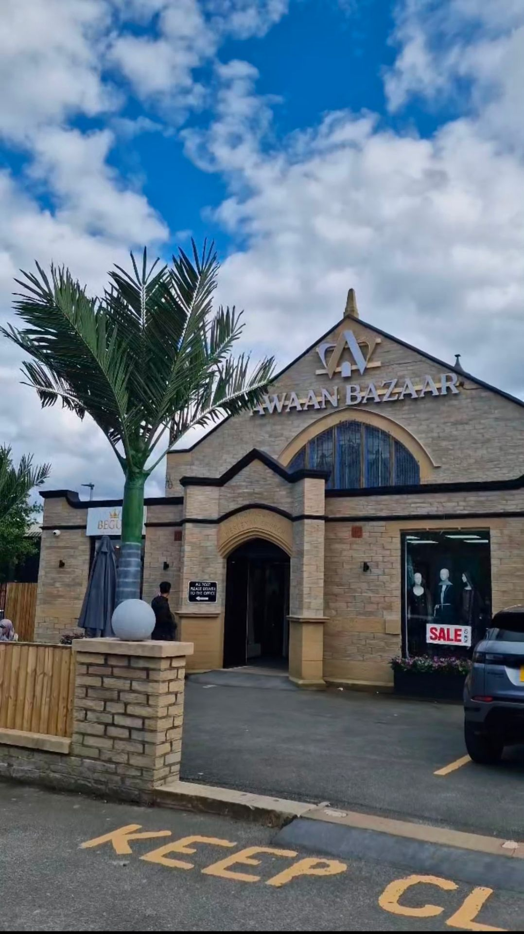 Awaan Bazaar exterior — brick building with arched entrance and palm tree on a bright day